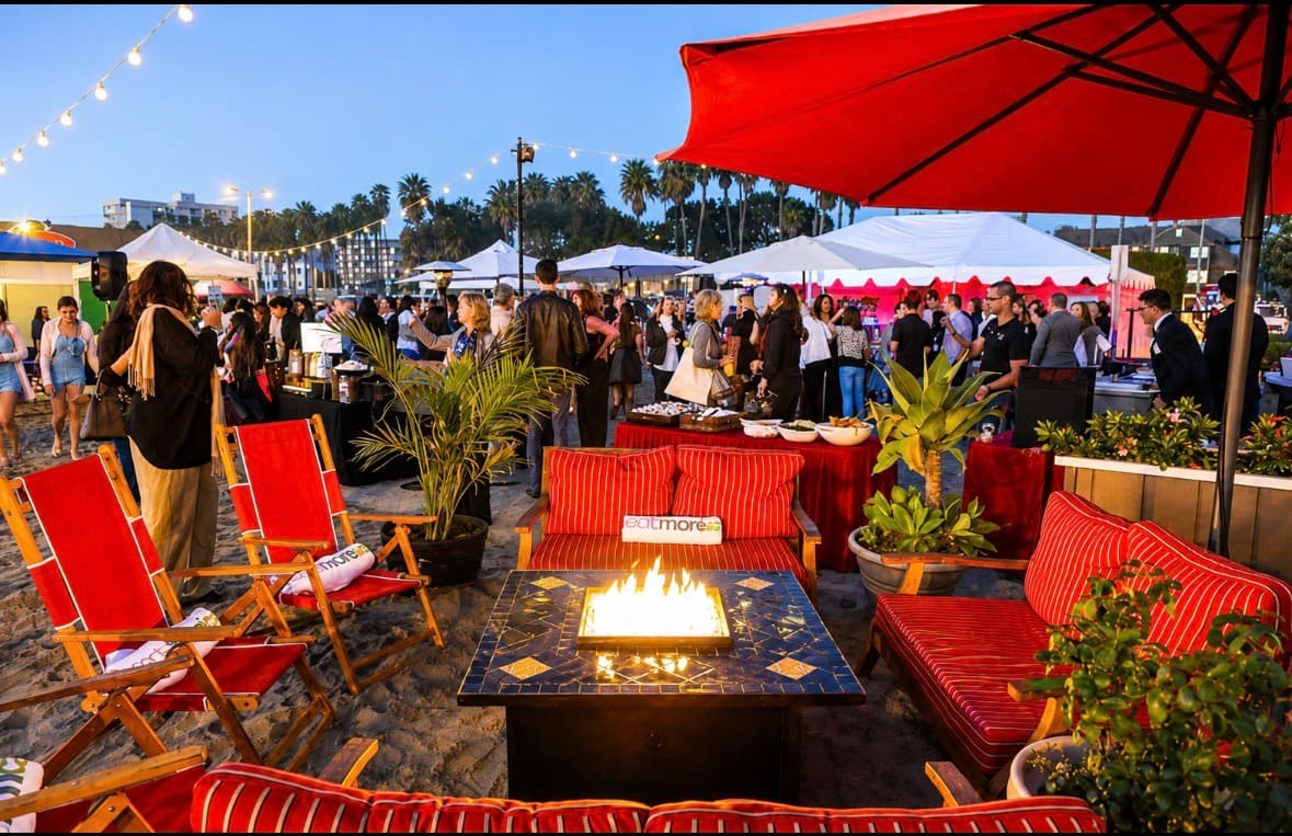 An evening beach lounge with fire-pit tables and string lights as the crowd gathers